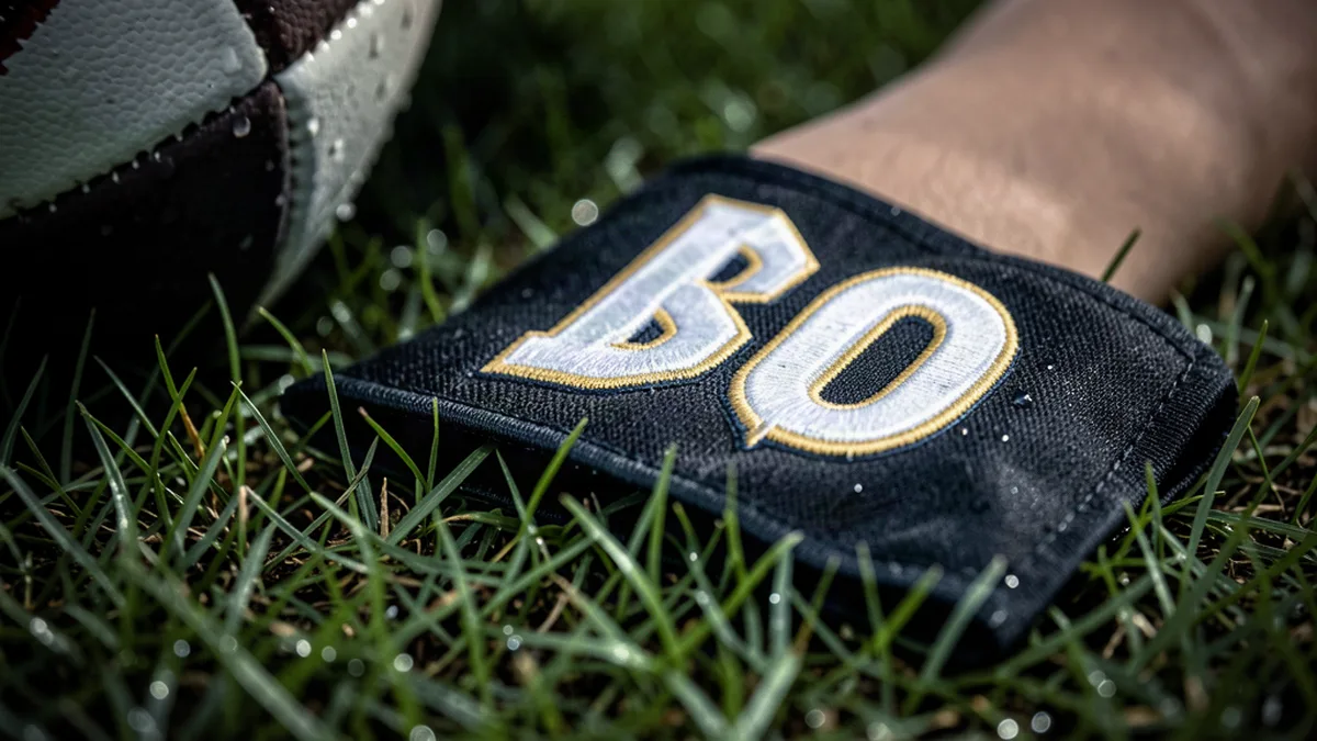 Brassard de capitaine posé sur l’herbe d’un terrain de Ligue 1
